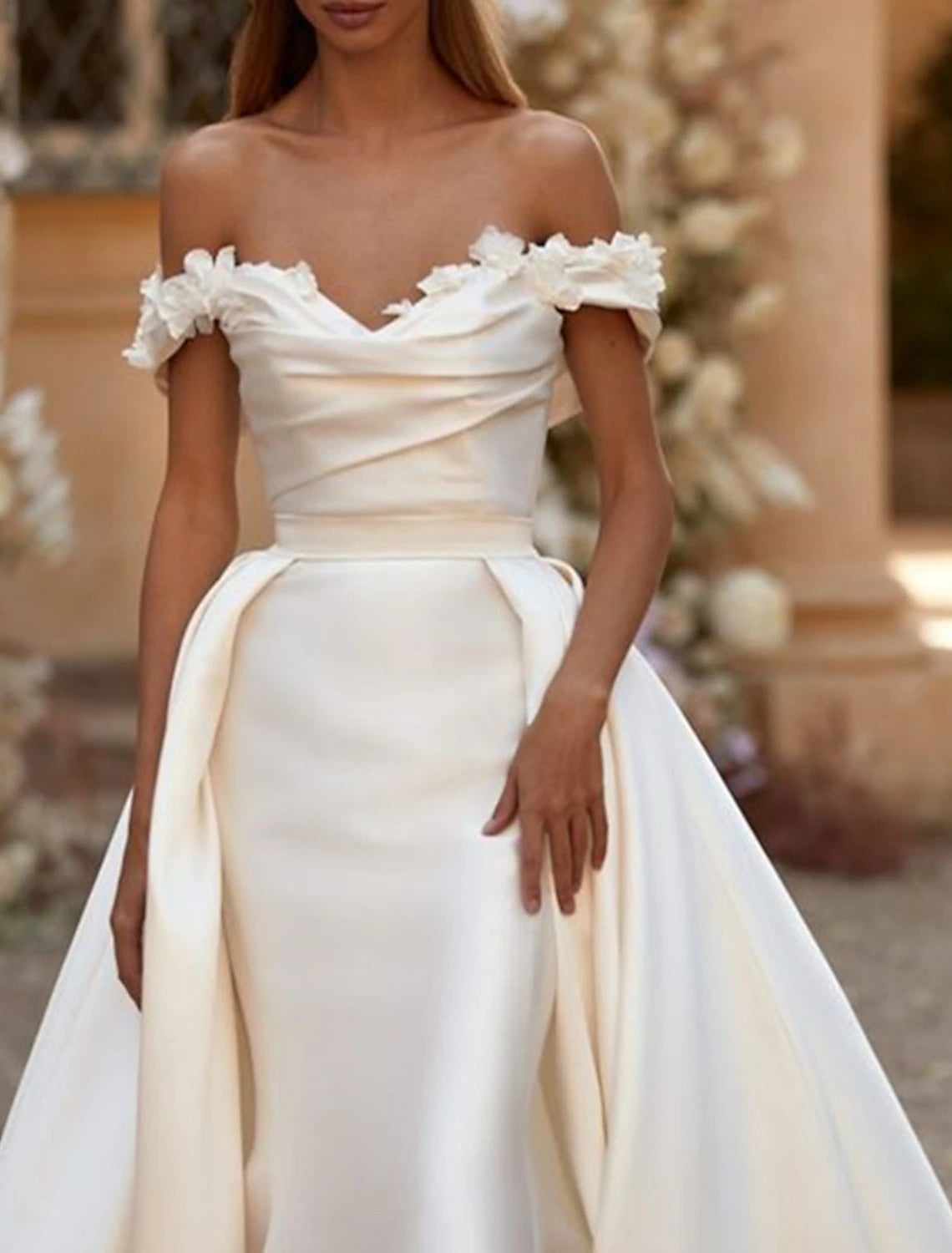 Back view of a white satin bridal gown with a flowing court train.