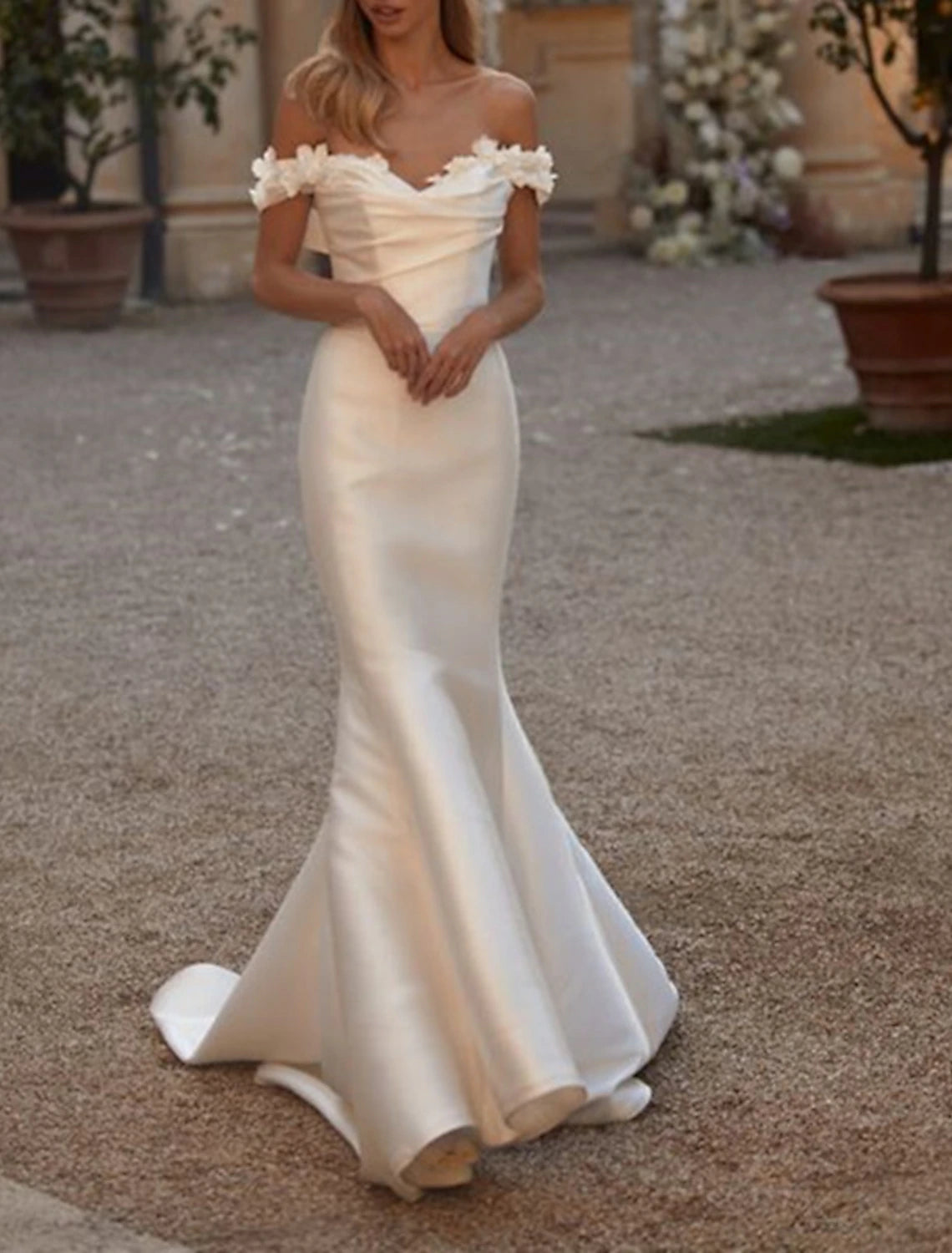 Close-up of ruched satin fabric on an off-shoulder wedding dress.