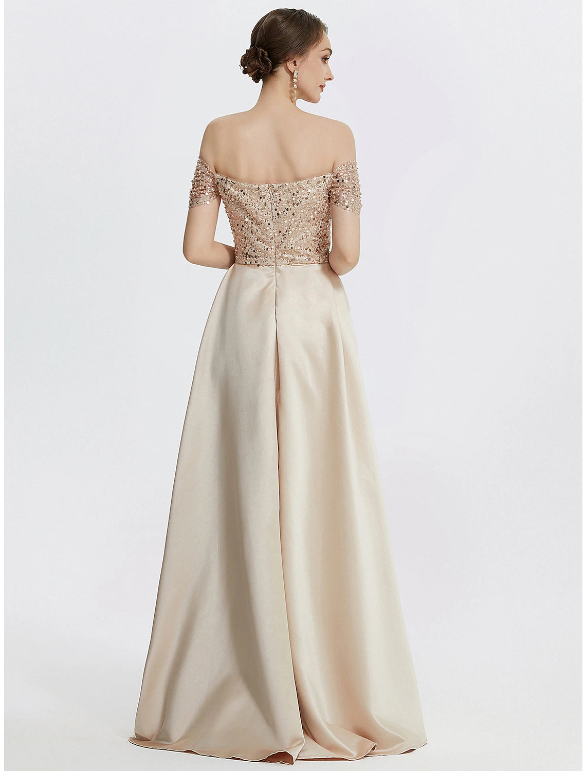Side view of a woman in a navy blue sequined off-shoulder gown, showing the elegant slit.