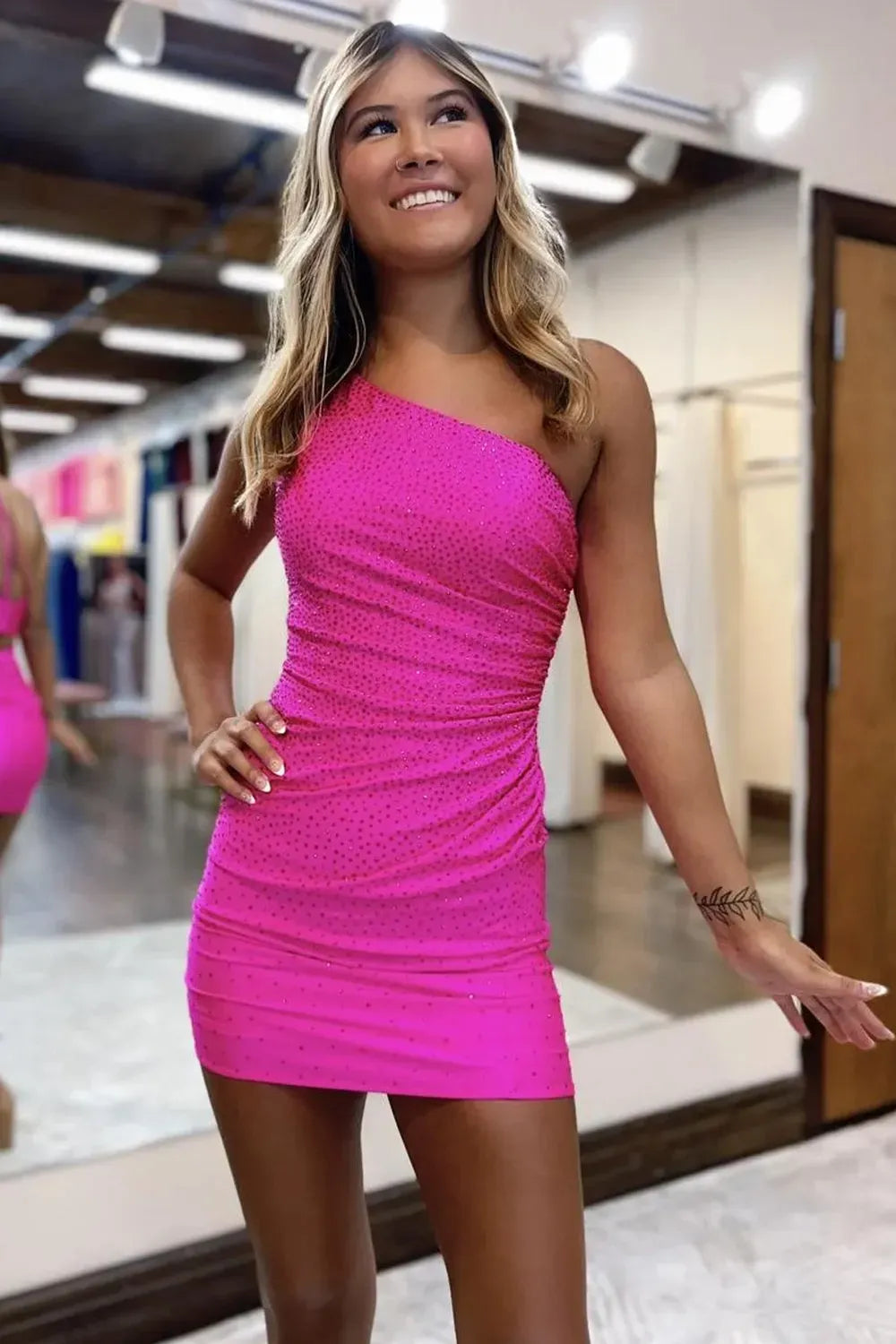 Model wearing an elegant one-shoulder short sheath homecoming dress with beading.
