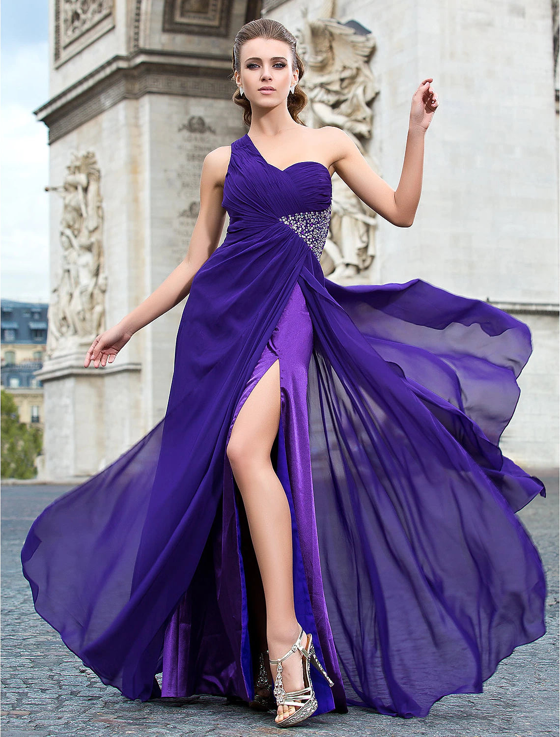 Woman wearing an elegant one-shoulder sheath evening dress with beading and a split front.