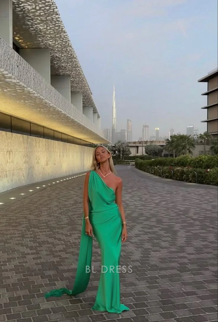 Elegant woman wearing a long green satin one-shoulder sheath dress, suitable for formal events.