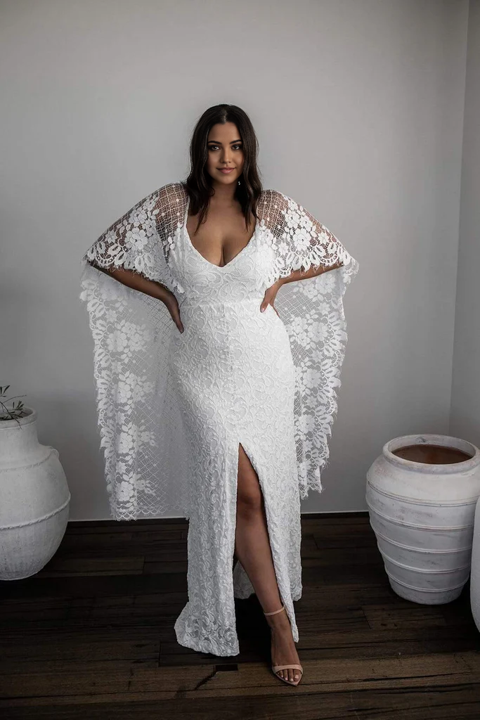 Side view of a bride wearing a lace sheath wedding dress with a flowing train.