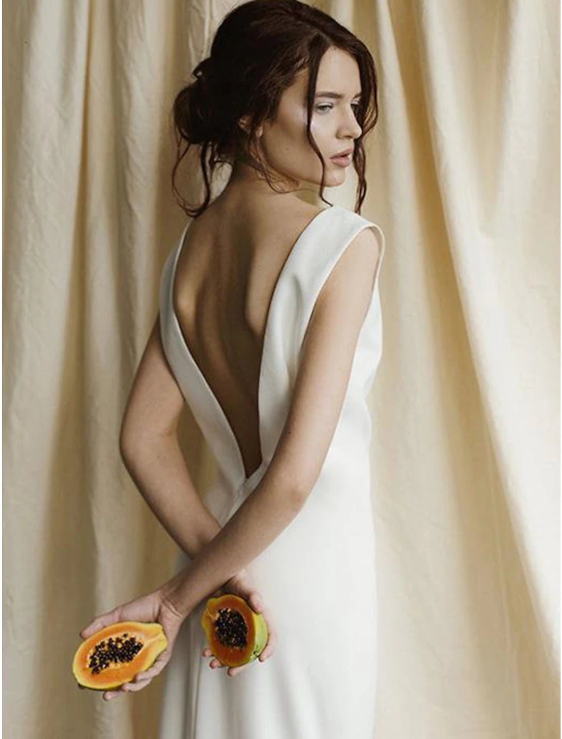 Side view of a sleeveless satin bridal gown with a sweep train.