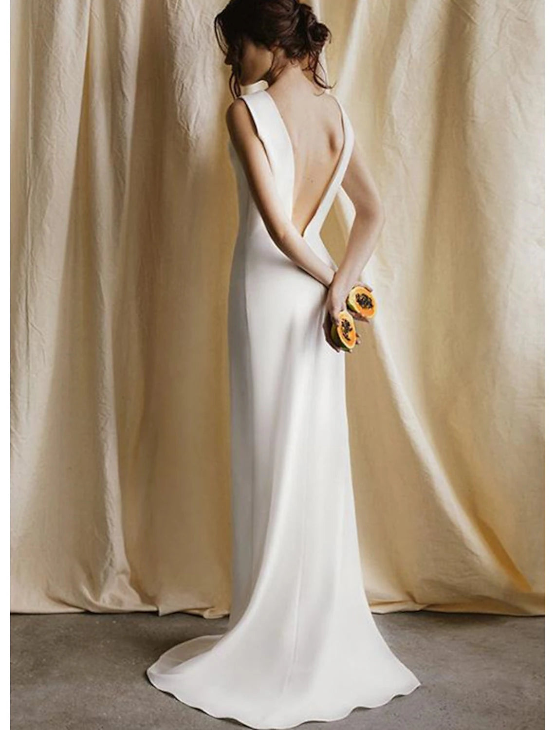 Back view of a sleeveless satin bridal gown, highlighting the open back and sweep train.