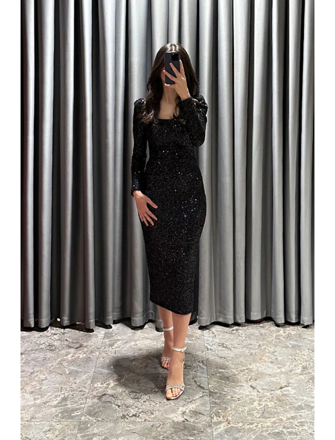 Detailed view of the long sleeve and sequin embellishments on the black gown.