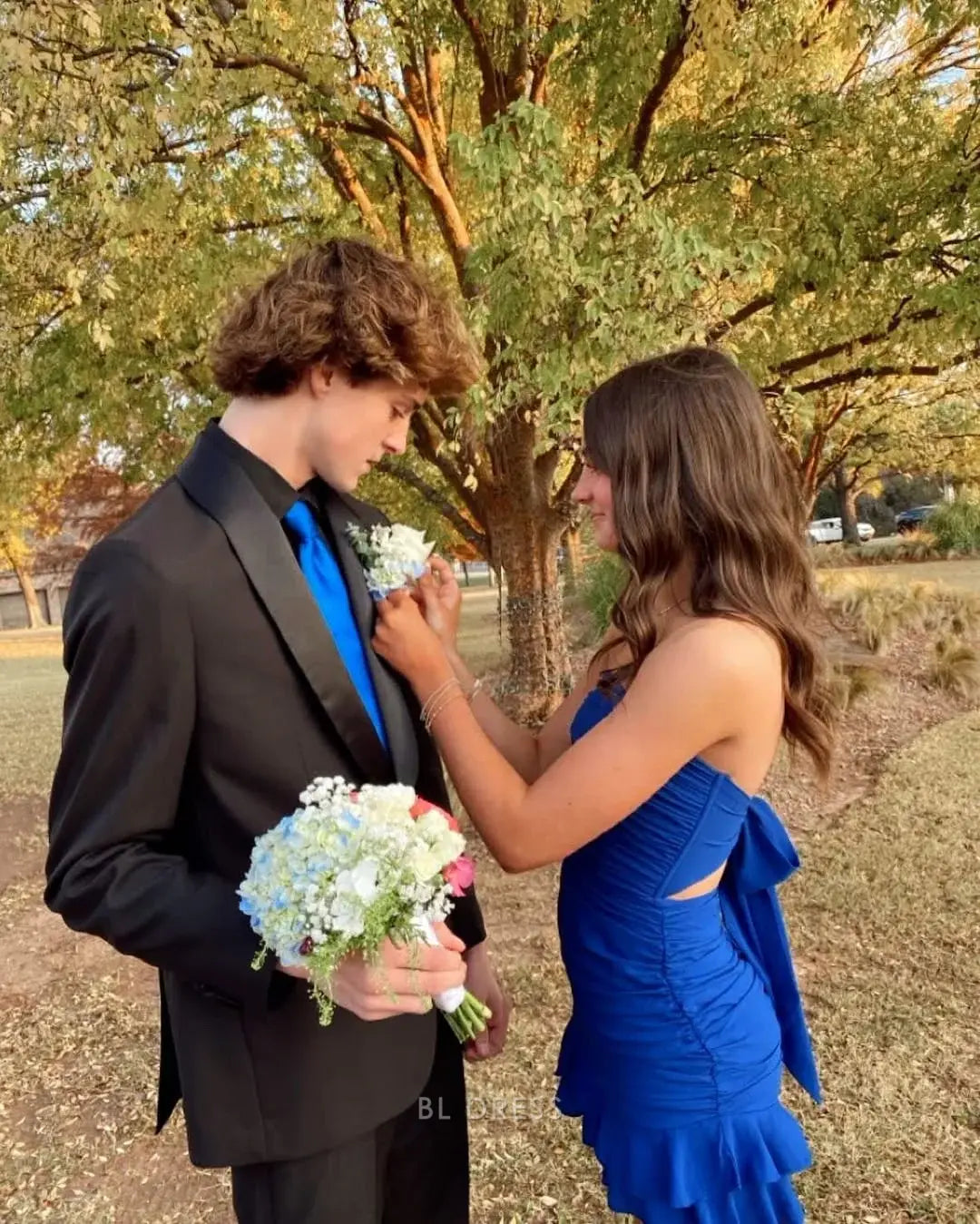 Model wearing a blue sheath strapless short dress, side view.