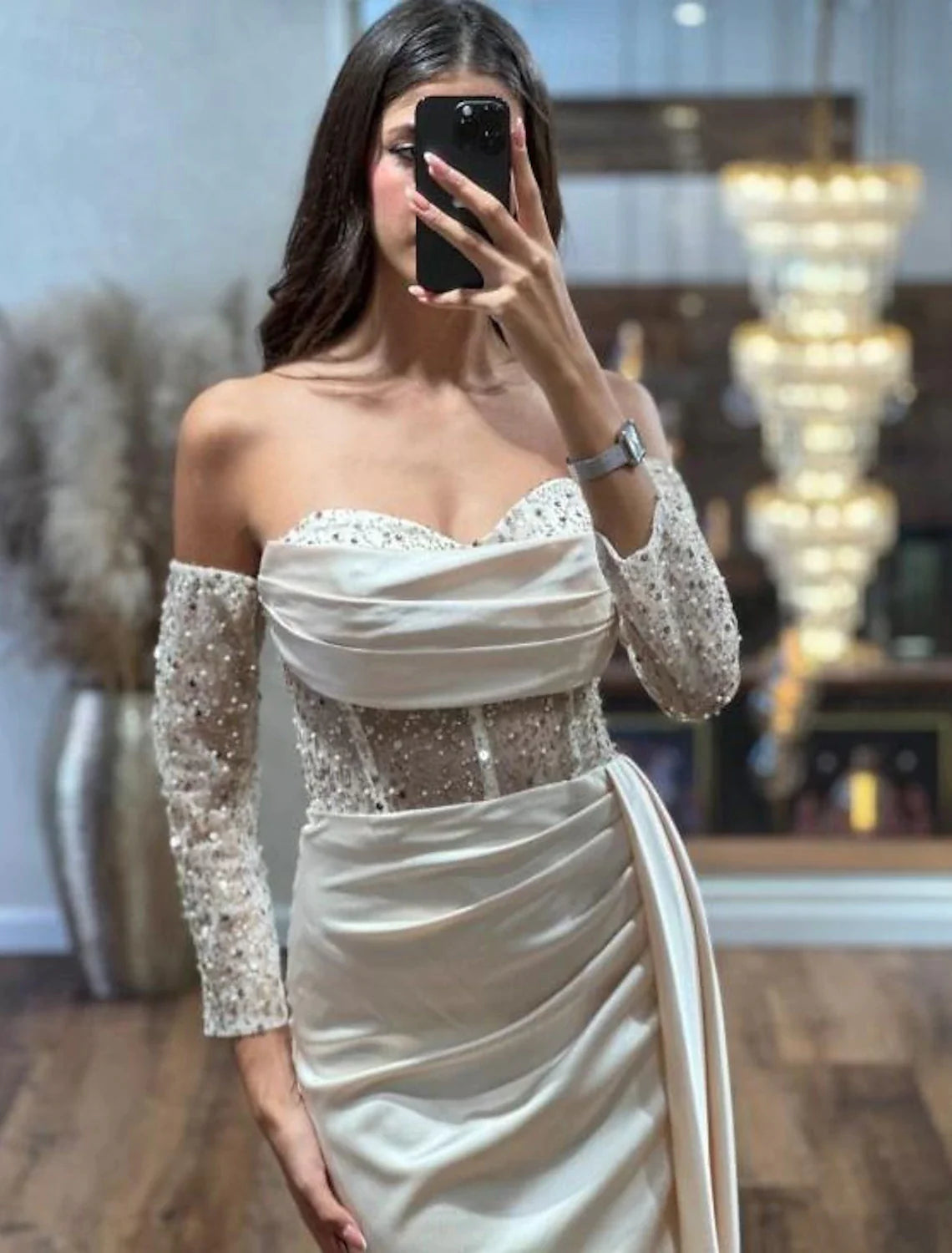 Side view of a formal satin gown with a high sequin slit and long sleeves.