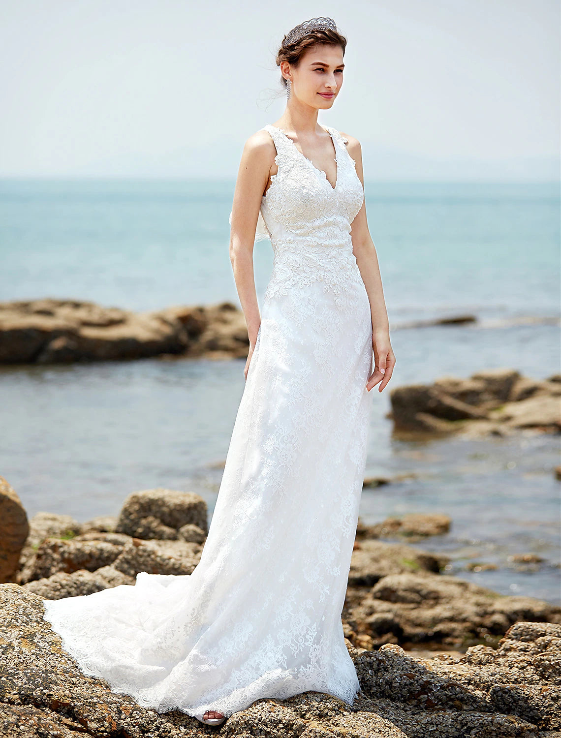 Bride posing in a sheath wedding dress with a flowing court train.