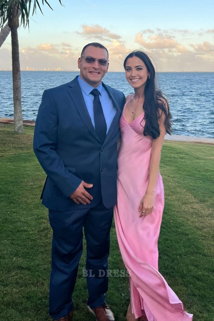 Woman wearing an elegant pink satin V-neck sheath long dress with a side split.