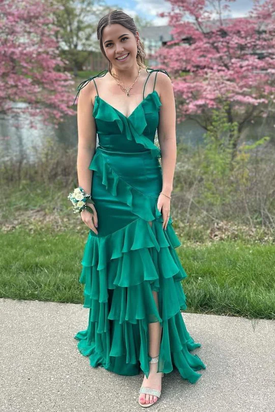 Model wearing an emerald green sheath V-neck formal dress with ruffle detail and high slit.