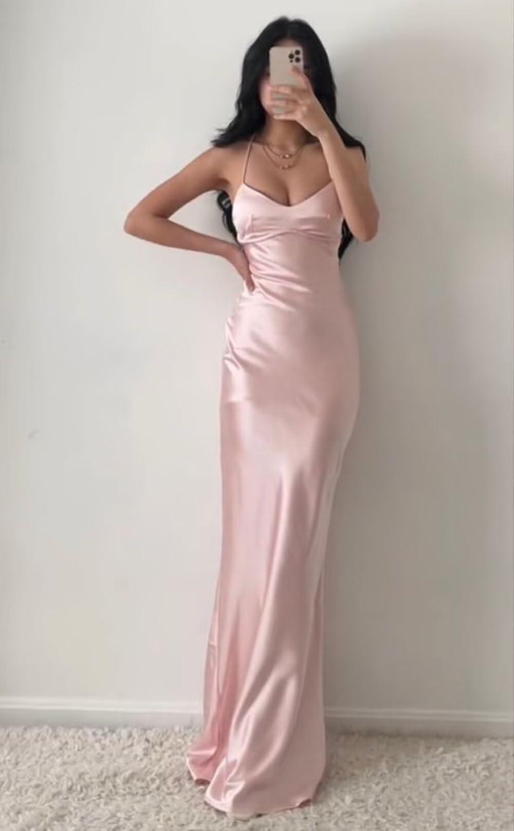 Woman wearing an elegant long satin sheath dress with a V-neck and spaghetti straps, featuring a high slit.