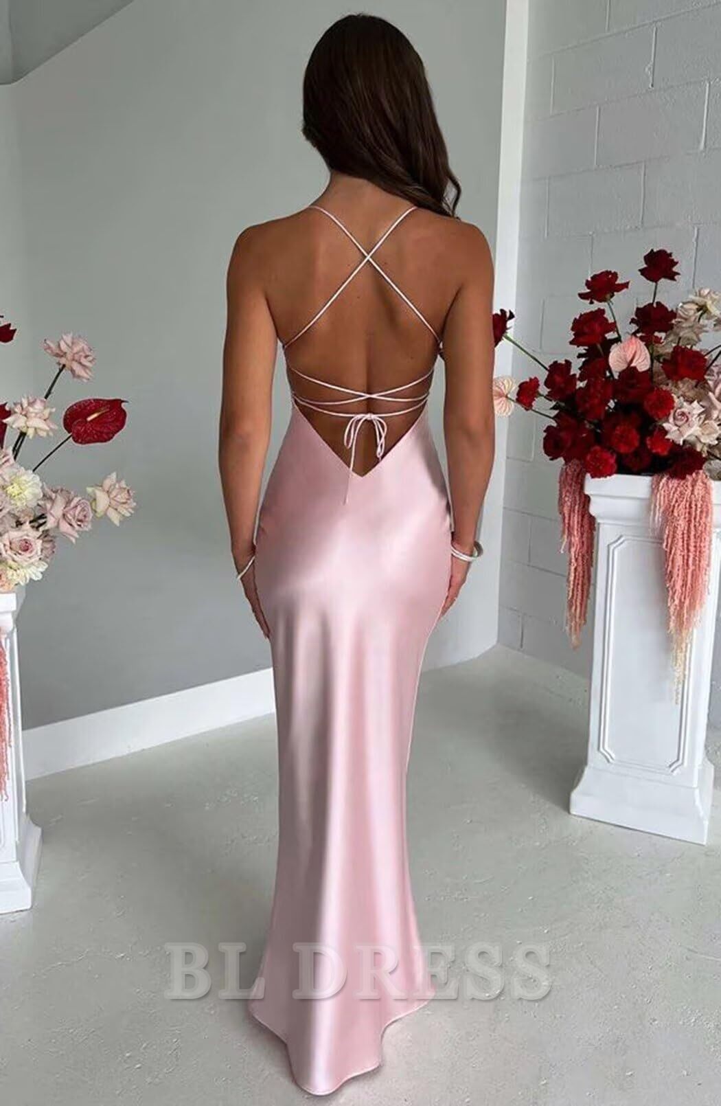 Back view of a woman in a long satin formal dress, showcasing the spaghetti straps and sleek silhouette.