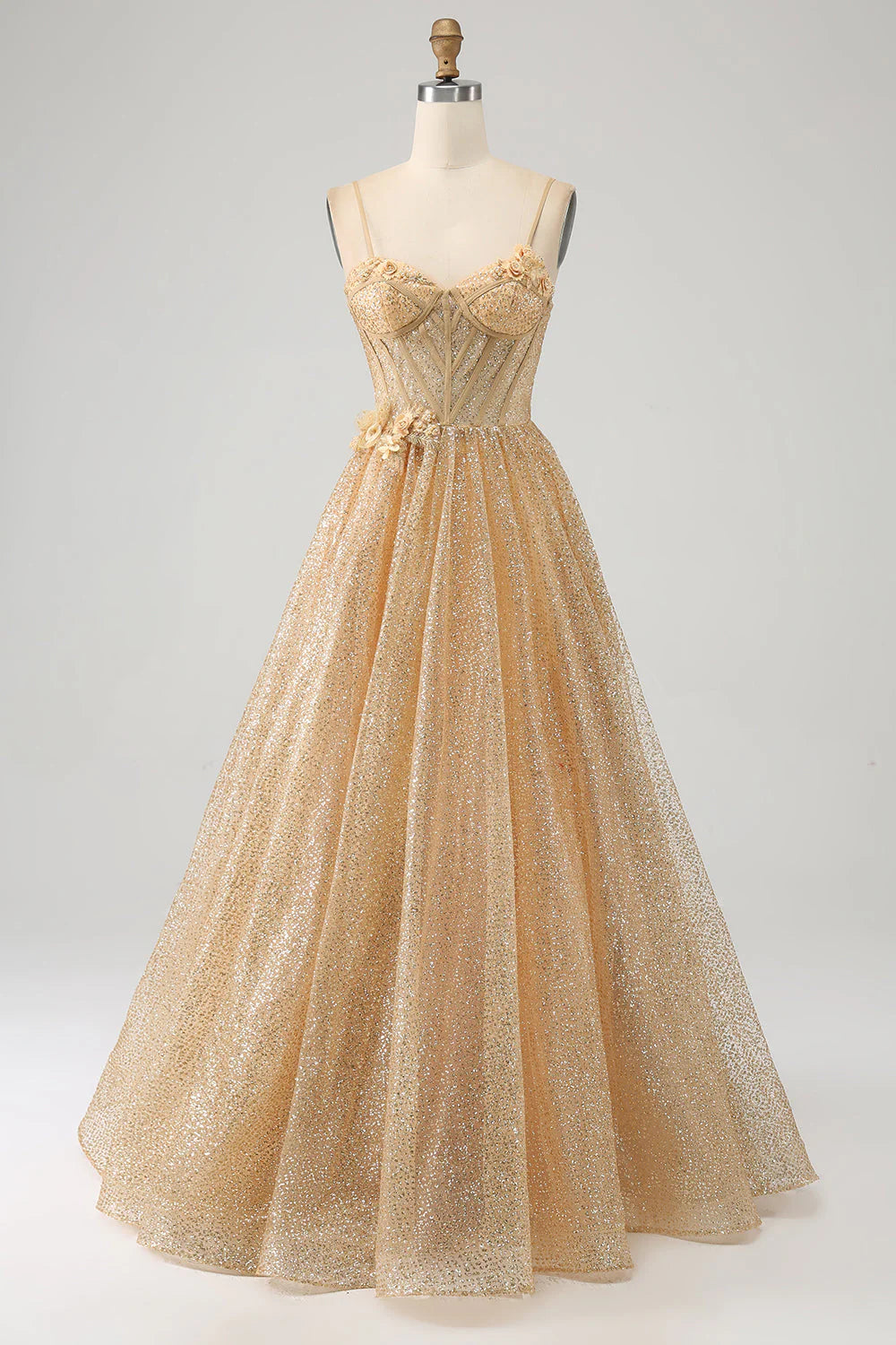 Model wearing a shimmering golden strapless prom dress with a corset bodice and floral appliques.