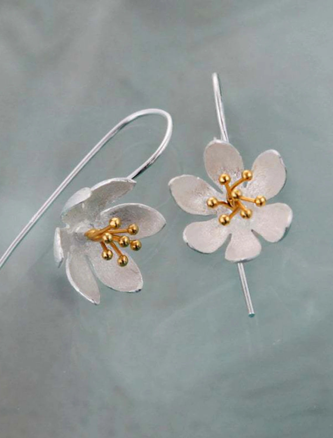 Elegant silver flower hoop earring on a white background.