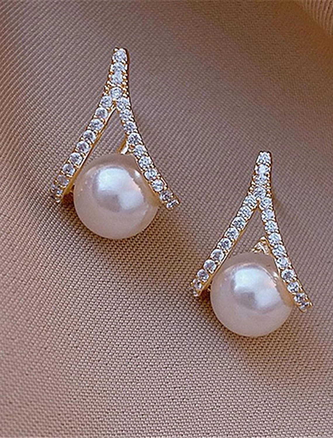 Woman wearing elegant silver pearl stud earrings, front view.