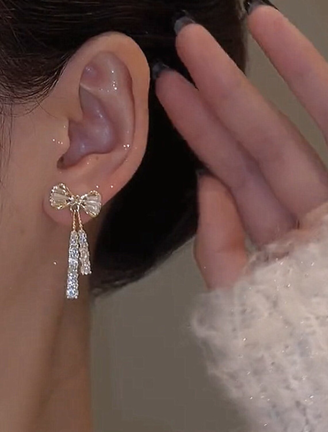 Pair of silver zircon bowknot drop earrings on a white background.
