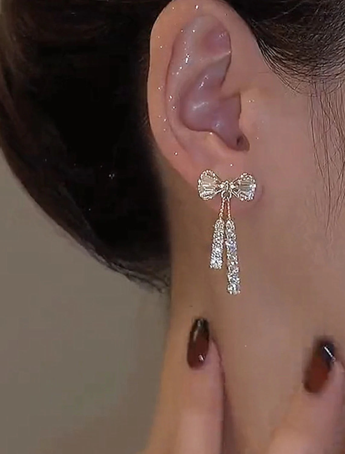 Side view of a silver zircon bowknot drop earring.