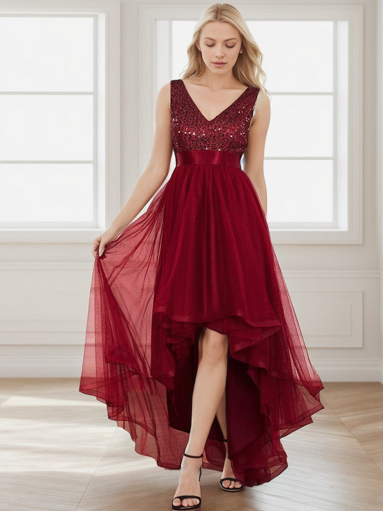 Woman wearing a sleeveless burgundy sequin tulle high-low evening gown.