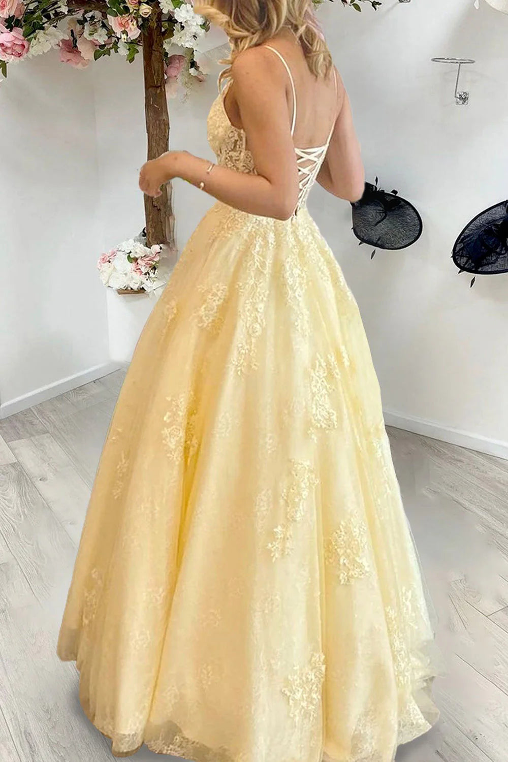 Full view of a long formal dress with spaghetti straps and intricate appliques.