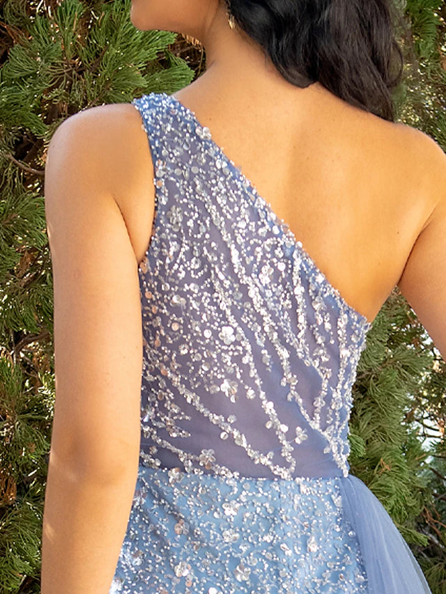 Back view of a woman in a black sequin one-shoulder mermaid evening gown, showcasing the floor-length silhouette.