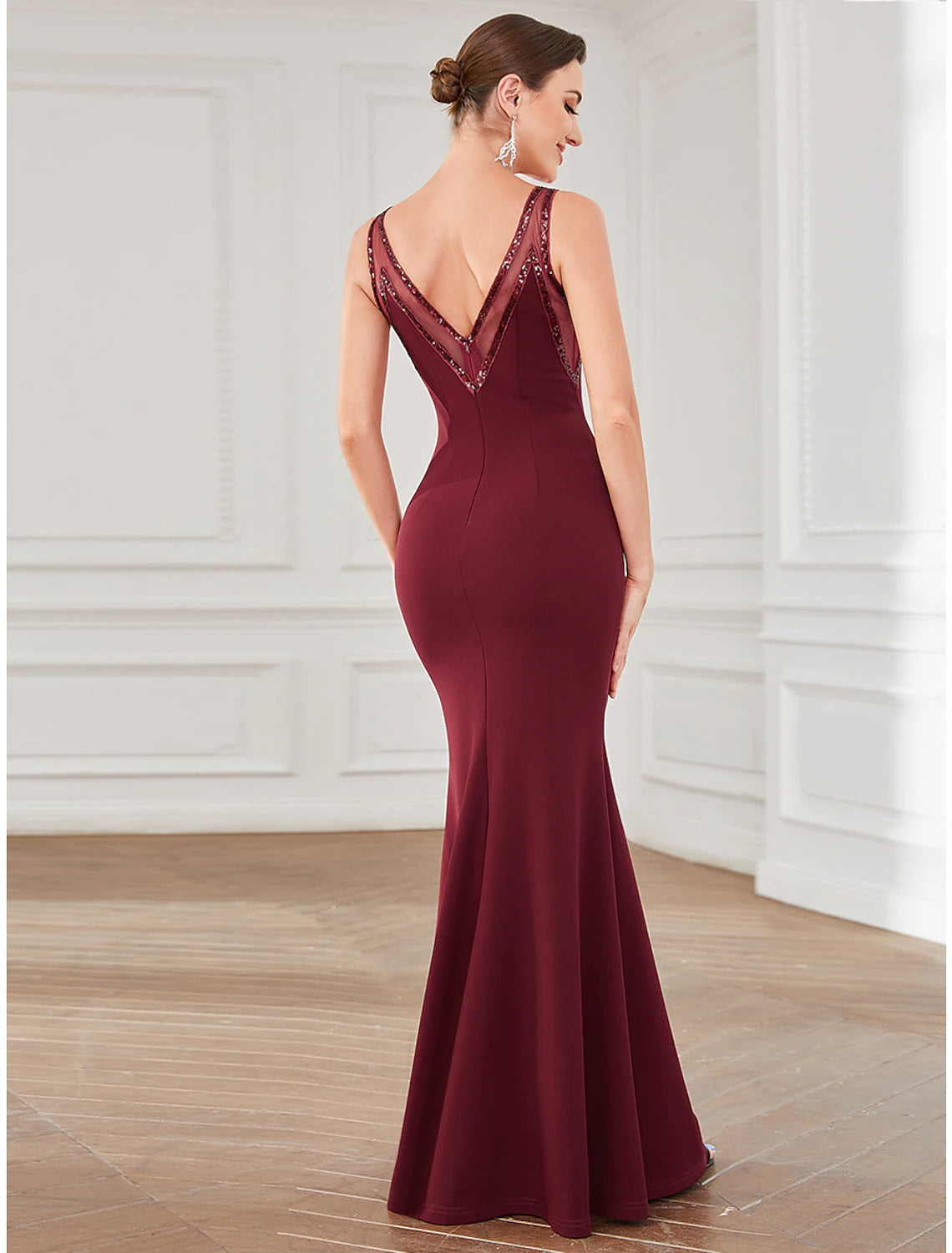 Side profile of a woman wearing a sleeveless crystal-adorned party gown.