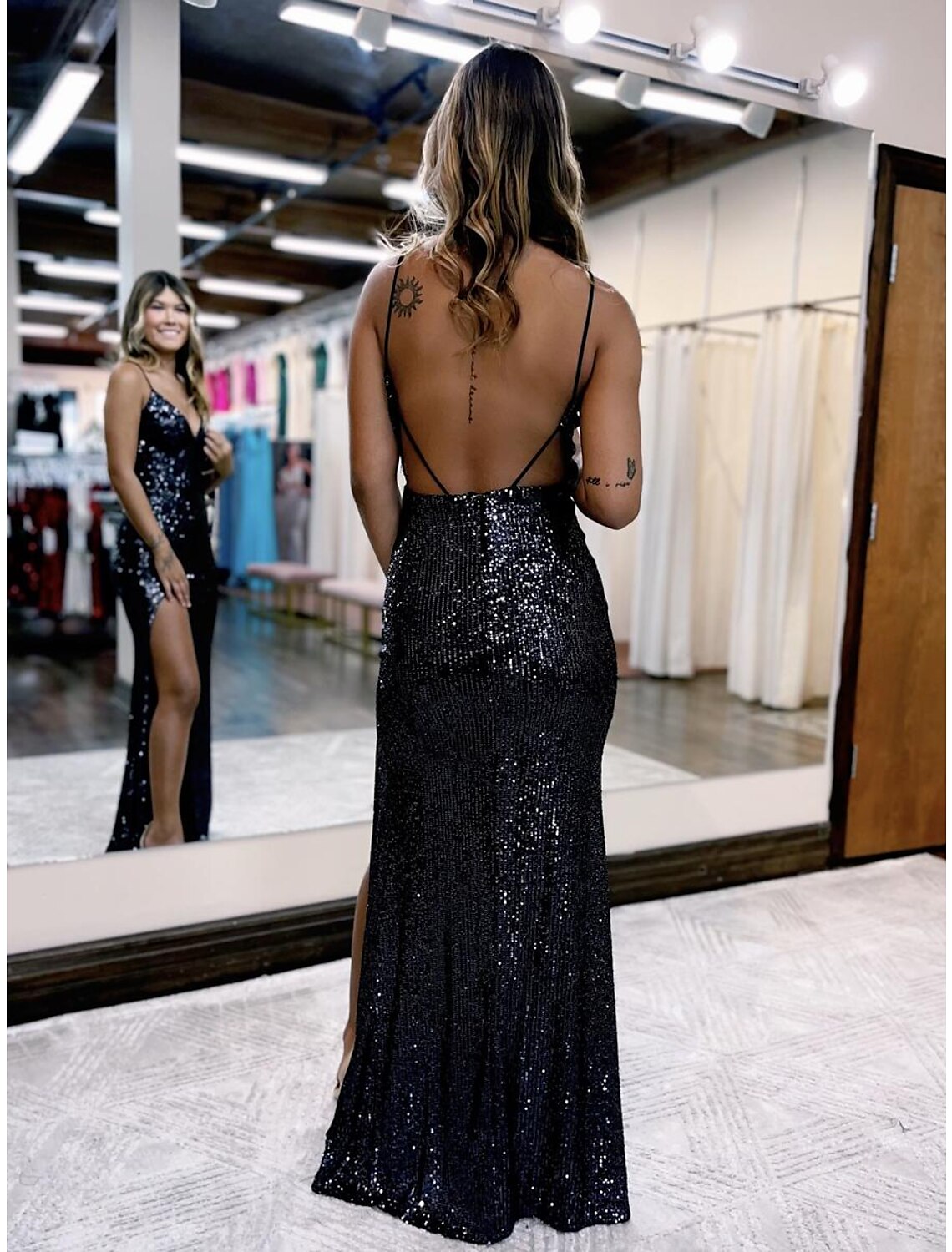 Back view of a woman in a sequined backless mermaid trumpet gown.