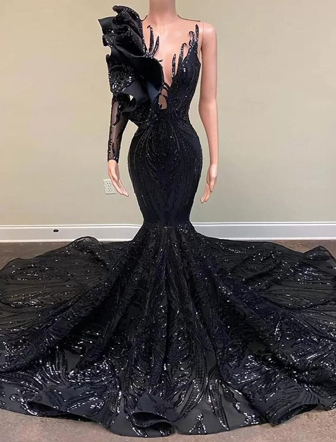 Model wearing a sparkly one-shoulder long sleeve mermaid evening gown with a court train.