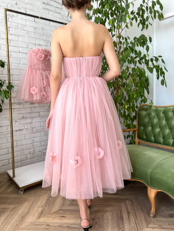 Back view of blush strapless gown with voluminous tea-length tulle skirt.