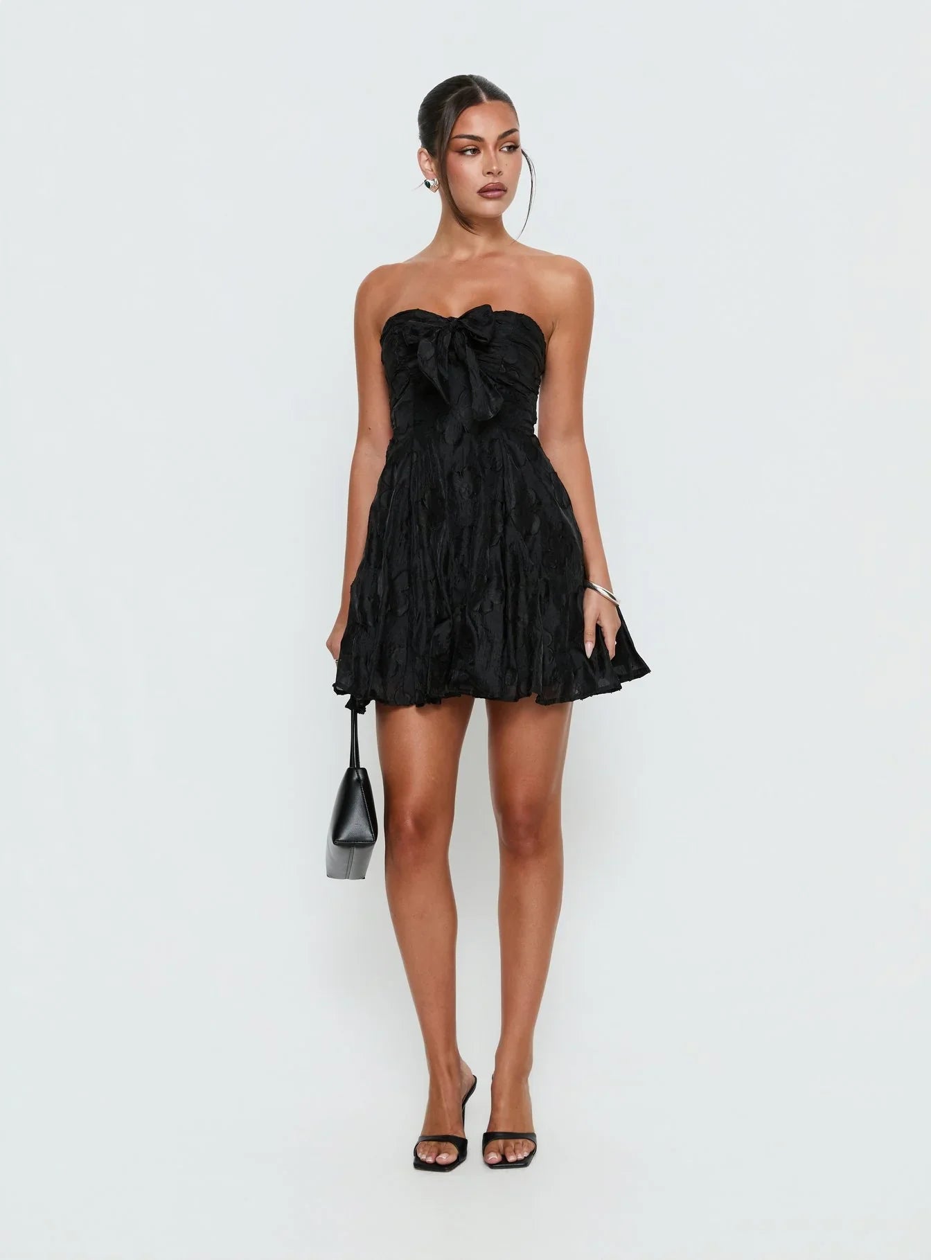 Black strapless A-line mini homecoming dress with a large bow detail on the front.