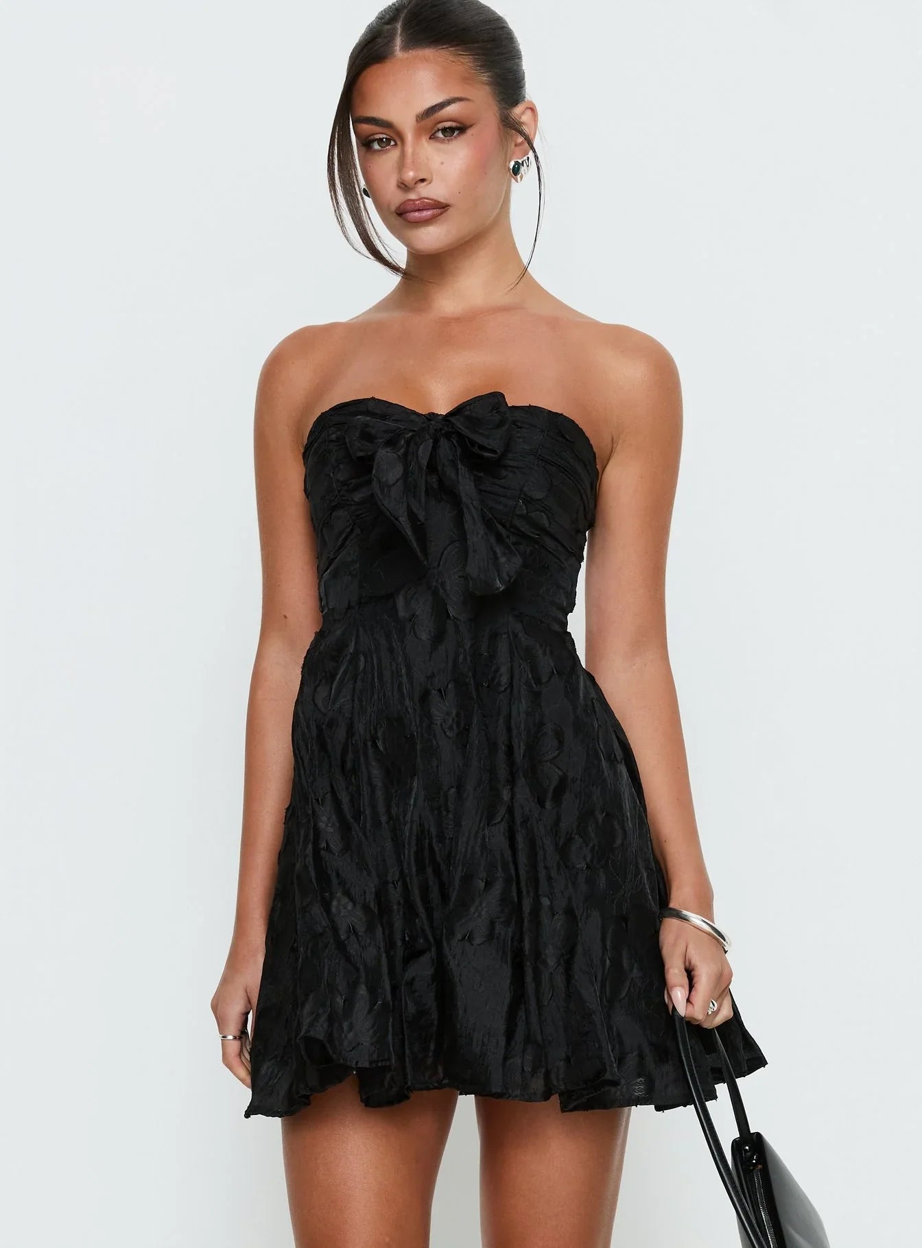 Side profile of a black strapless A-line mini dress, highlighting the floral jacquard fabric.