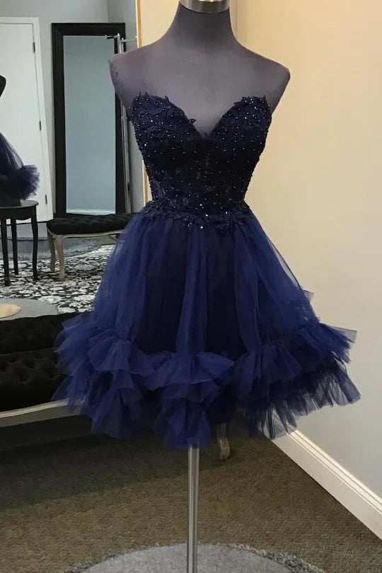 Model wearing a short strapless A-line homecoming dress with a lace top and ruffle skirt.