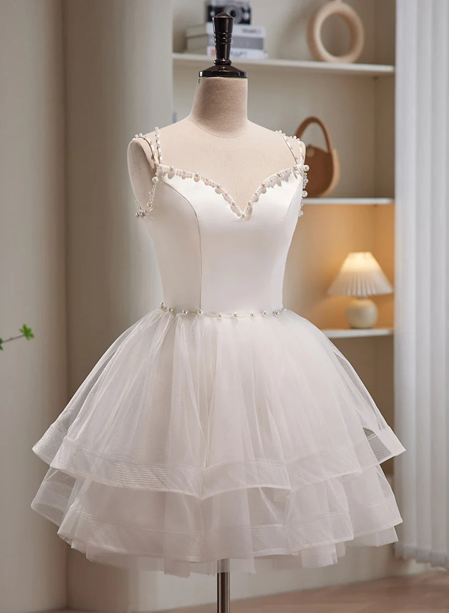 Side view of a model in a white short strapless formal dress with tulle skirt.