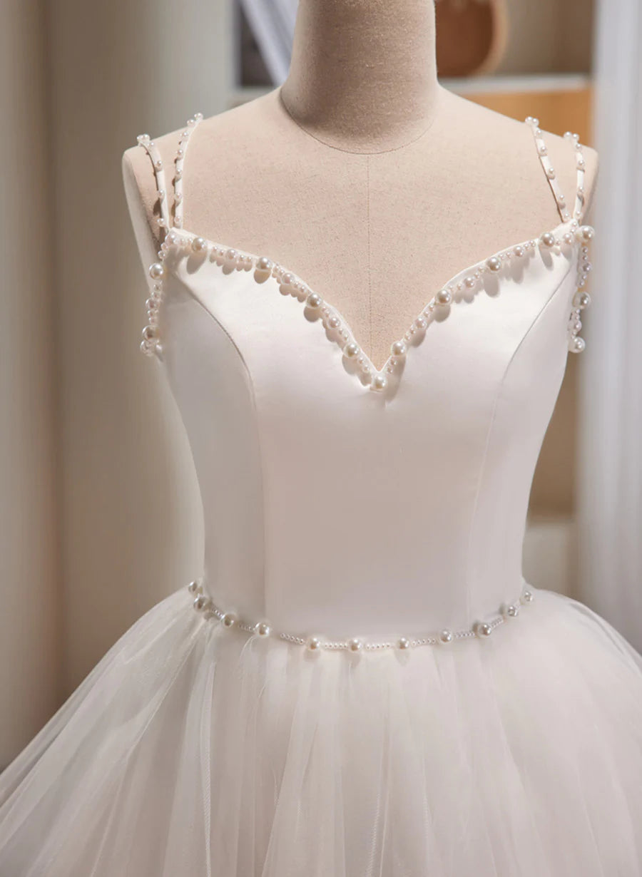 Close-up of the beaded detail on the bodice of a white short prom dress.