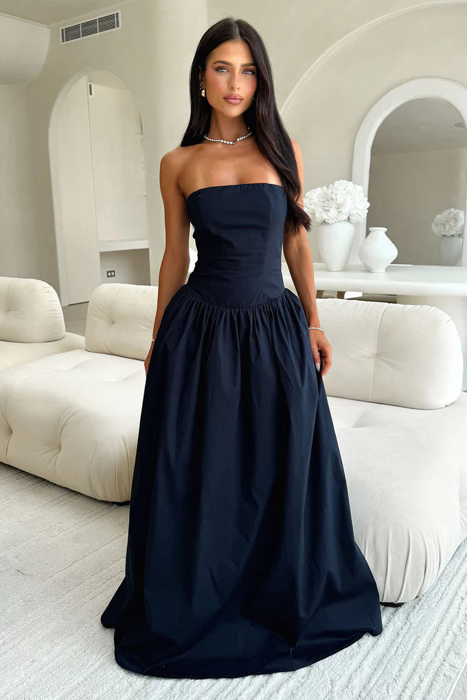 Woman wearing a navy blue strapless A-line maxi dress with a corset bodice.