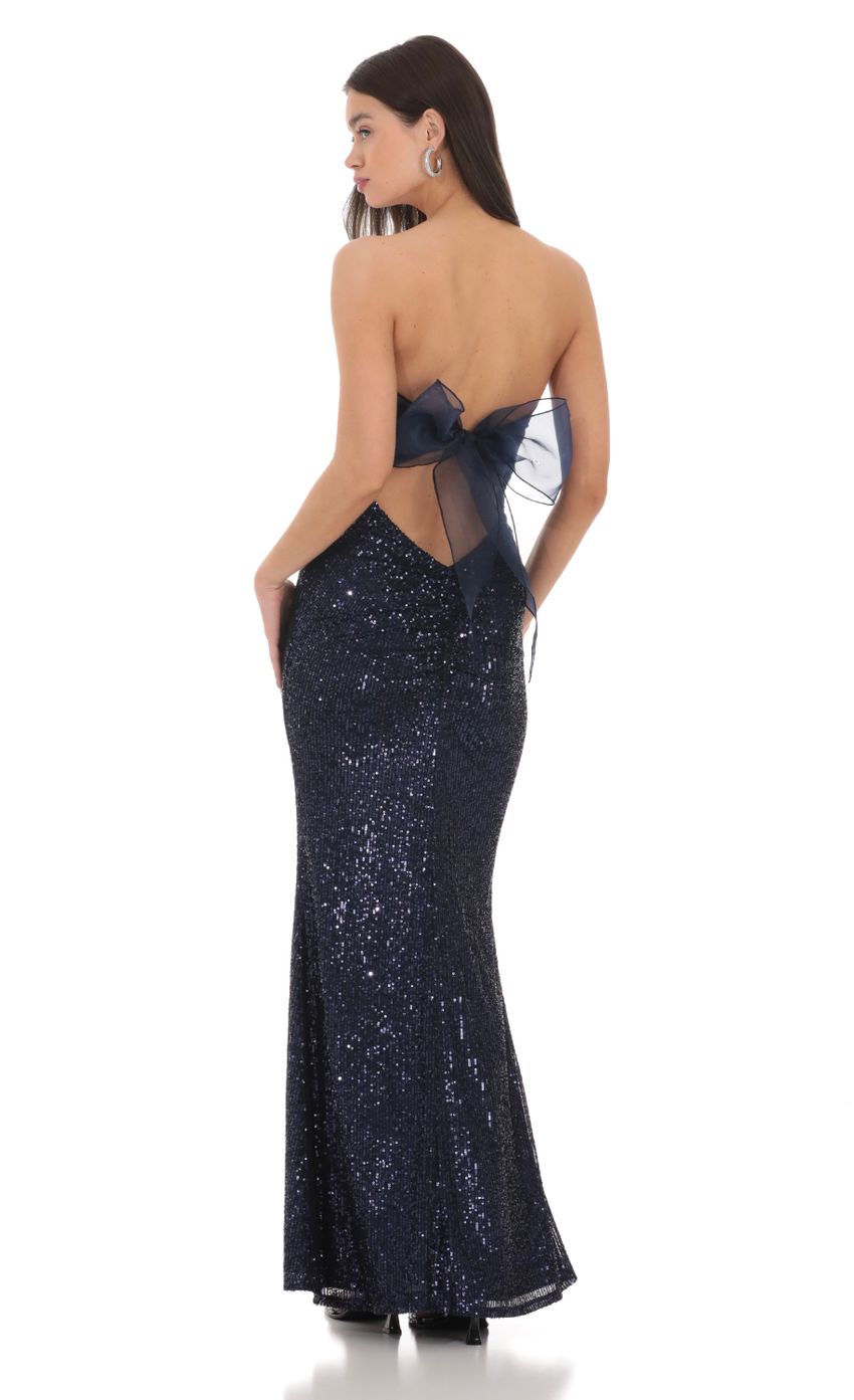 Full view of a woman wearing the navy and white strapless corset maxi dress with a back bow.