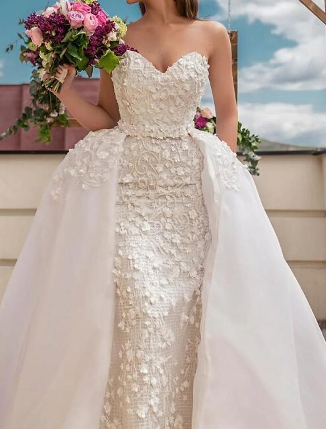 Close-up of the elegant strapless lace ball gown wedding dress, highlighting the delicate lace patterns and flowing skirt.