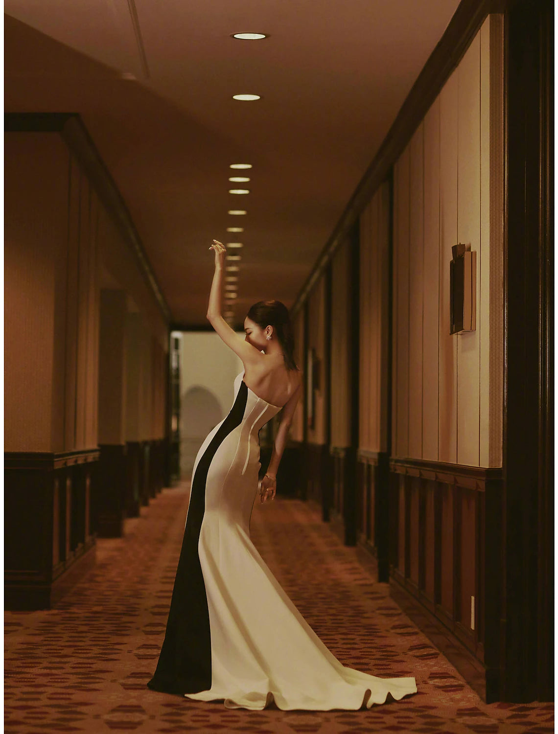 Side view of a woman wearing a strapless color block mermaid dress.