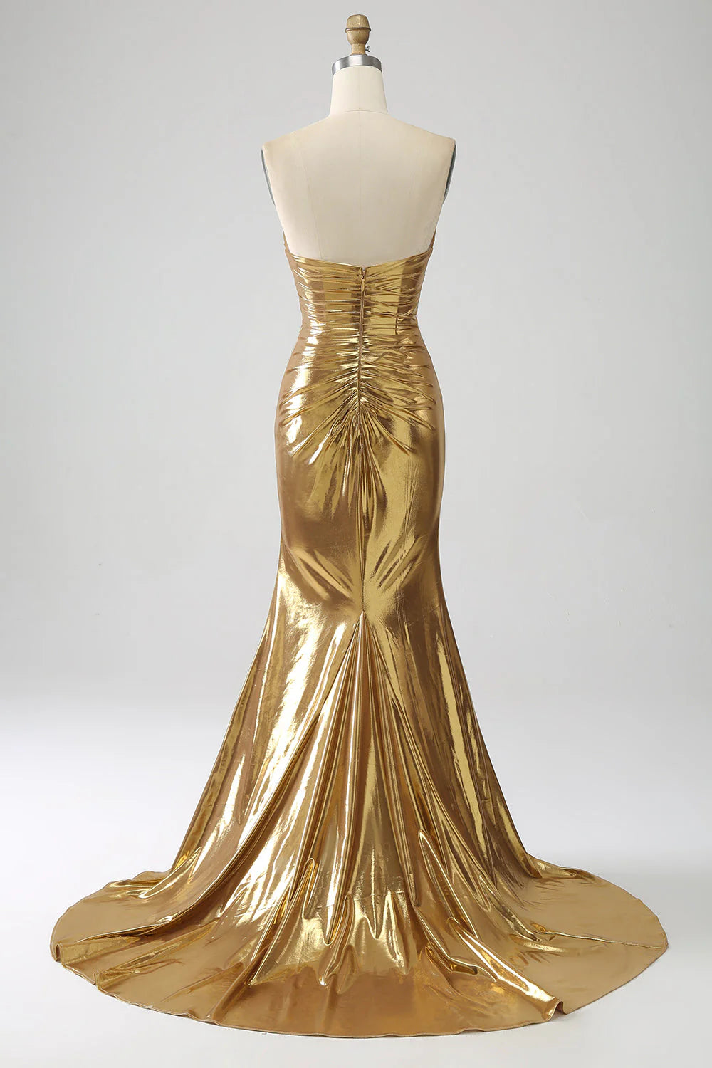 Side view of a woman wearing a golden strapless mermaid gown, showcasing the flowing skirt.