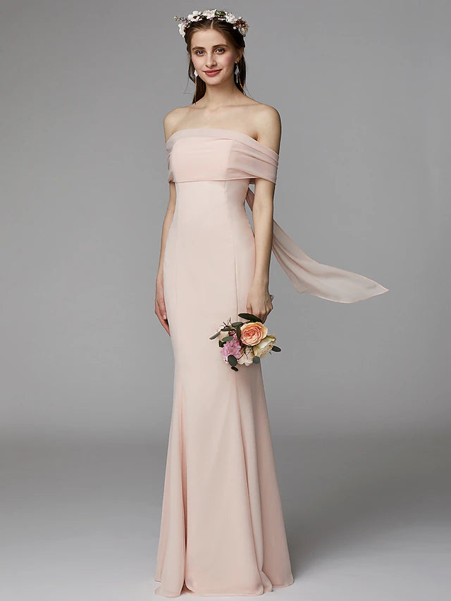 Woman wearing an elegant strapless mermaid trumpet bridesmaid dress with a sash.
