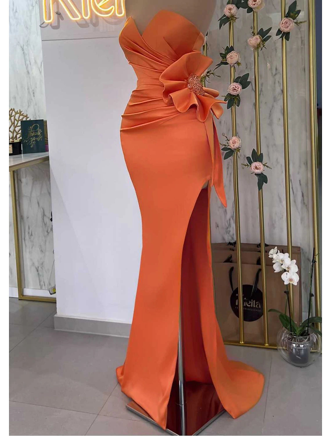 Elegant strapless mermaid trumpet evening gown with floral details and a high slit.