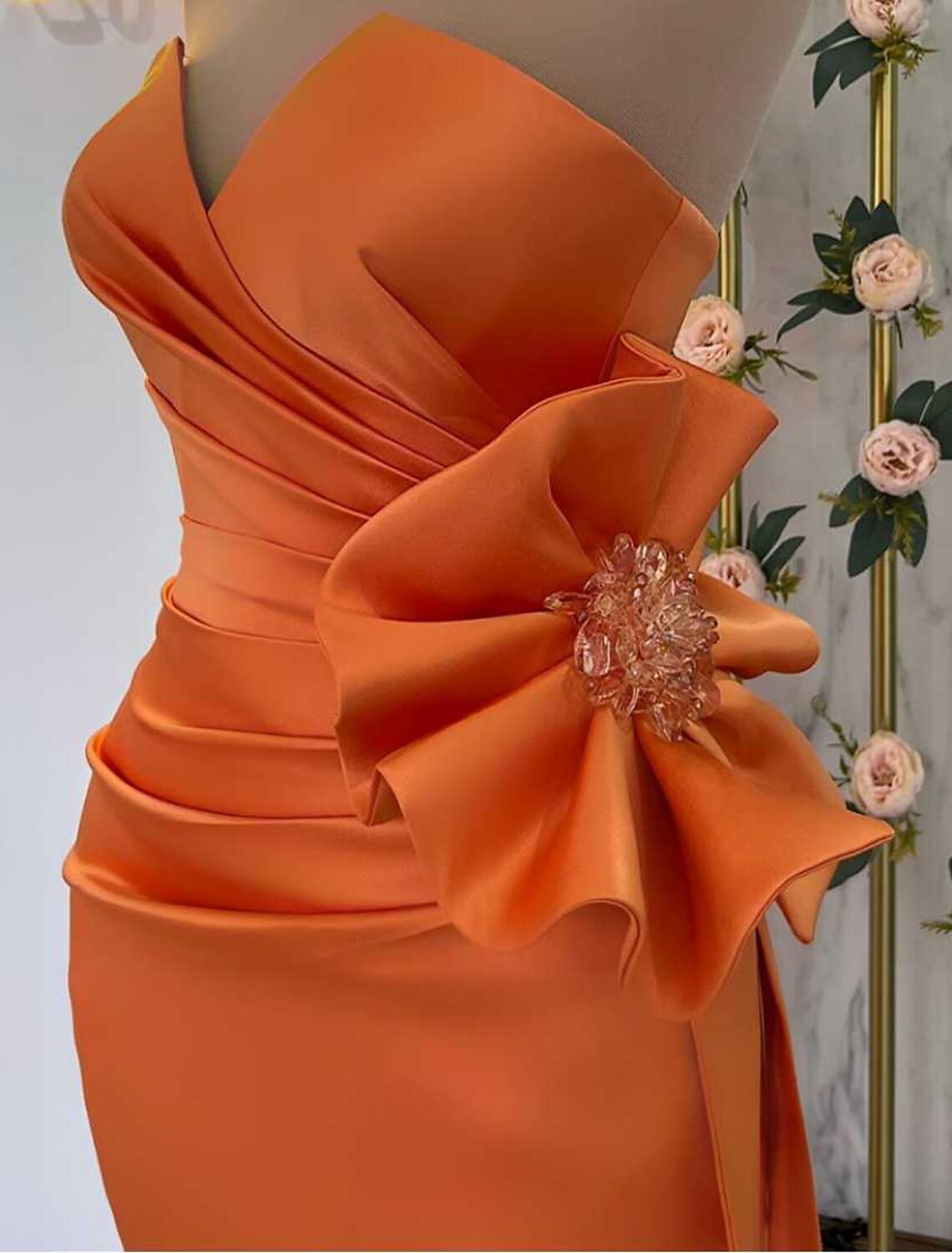 Close-up of the floral satin fabric and slit detail on the evening gown.