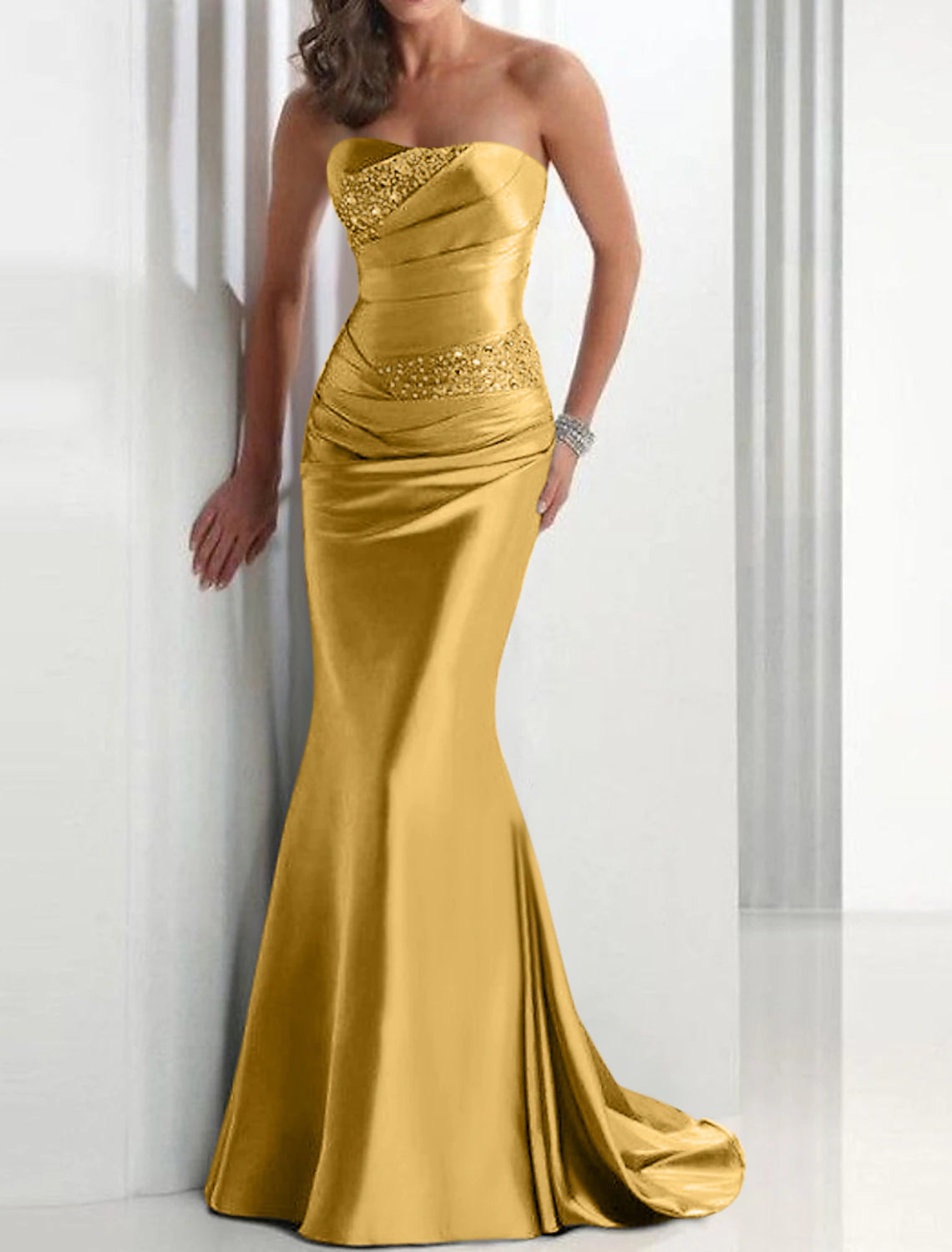A woman wearing the strapless mermaid trumpet evening dress, showing the back detail and sweep train.