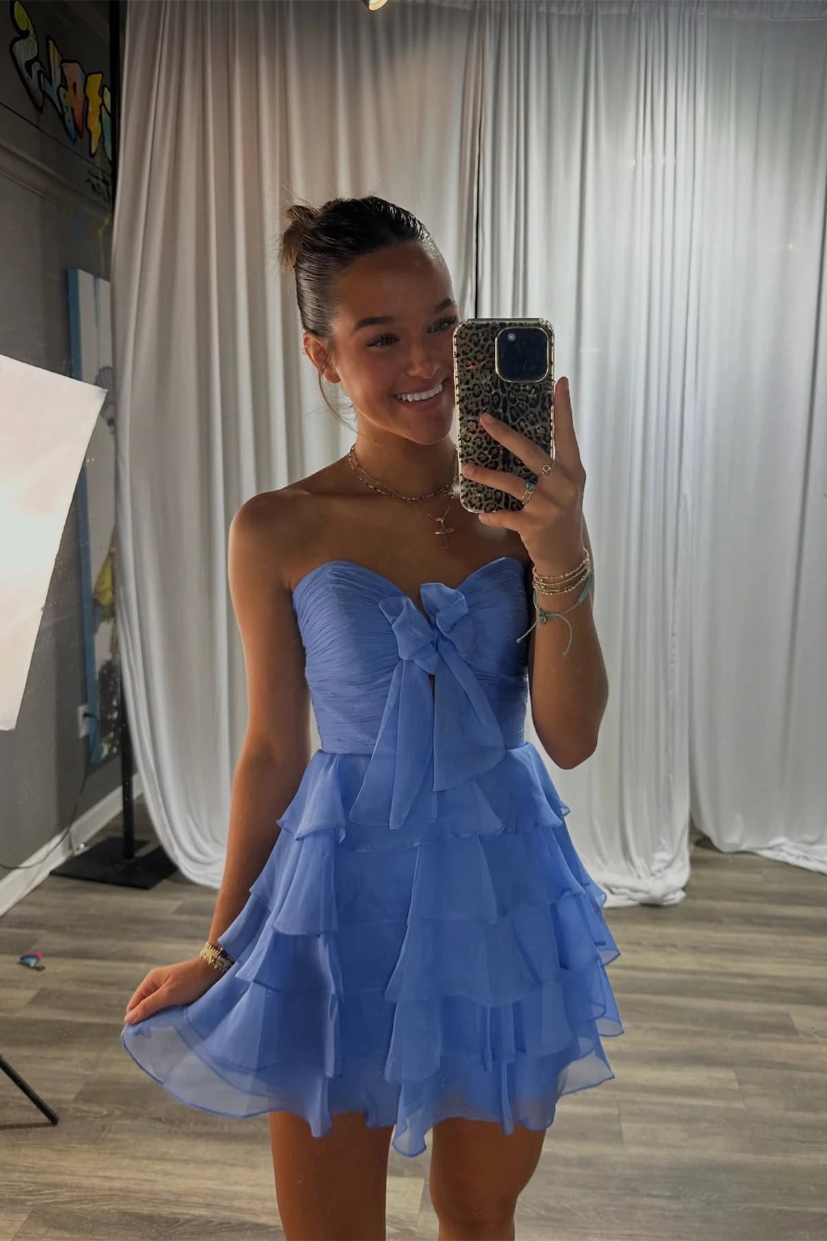 Lavender strapless short dress with pleated tiers and a bow, worn by a model.