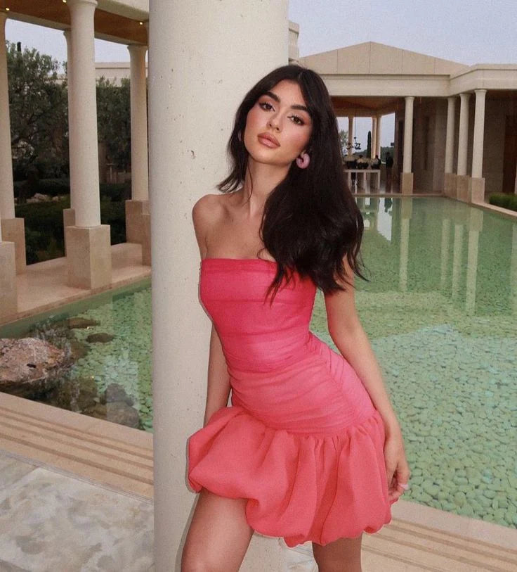 Model wearing a pink strapless ruched homecoming dress with a bubble hem.