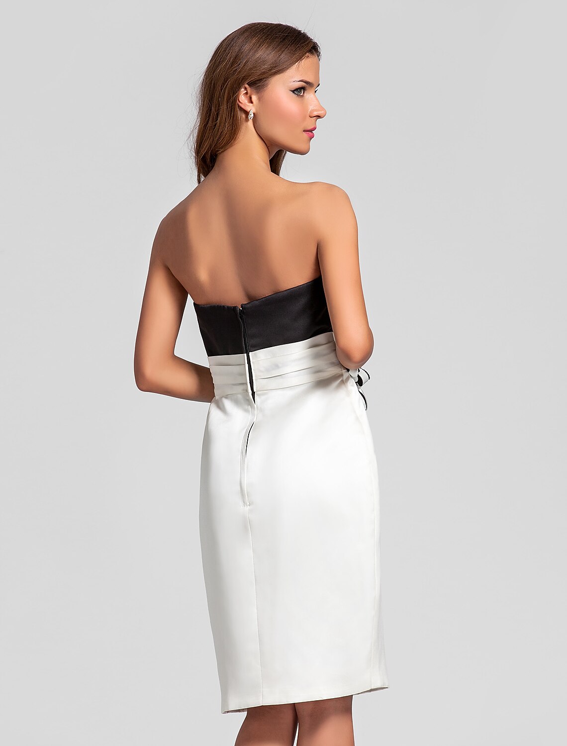 Model posing in a sophisticated strapless knee-length satin dress.