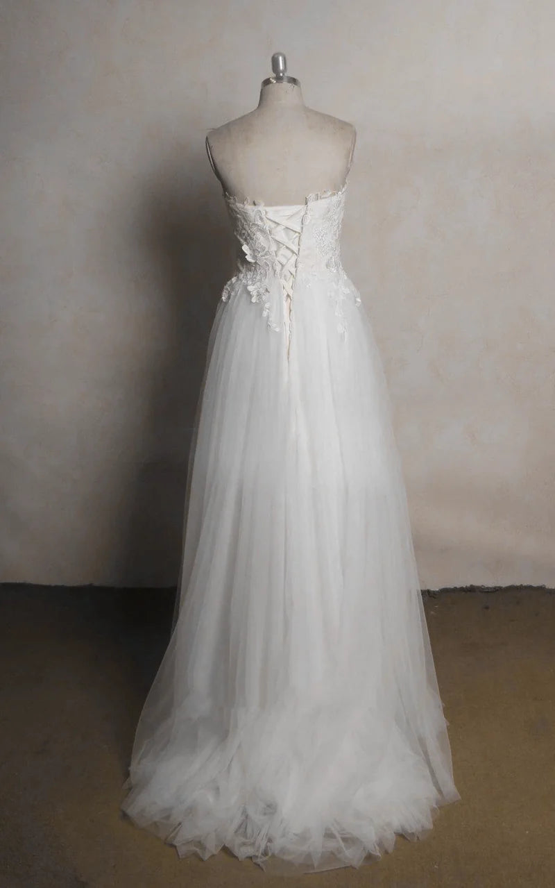 Back view of a white A-line bridal gown with flowing tulle skirt and delicate lace details.