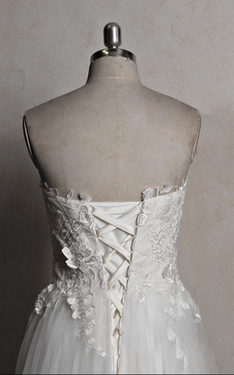 Close-up of the intricate lace and bead embellishments on a satin wedding dress.