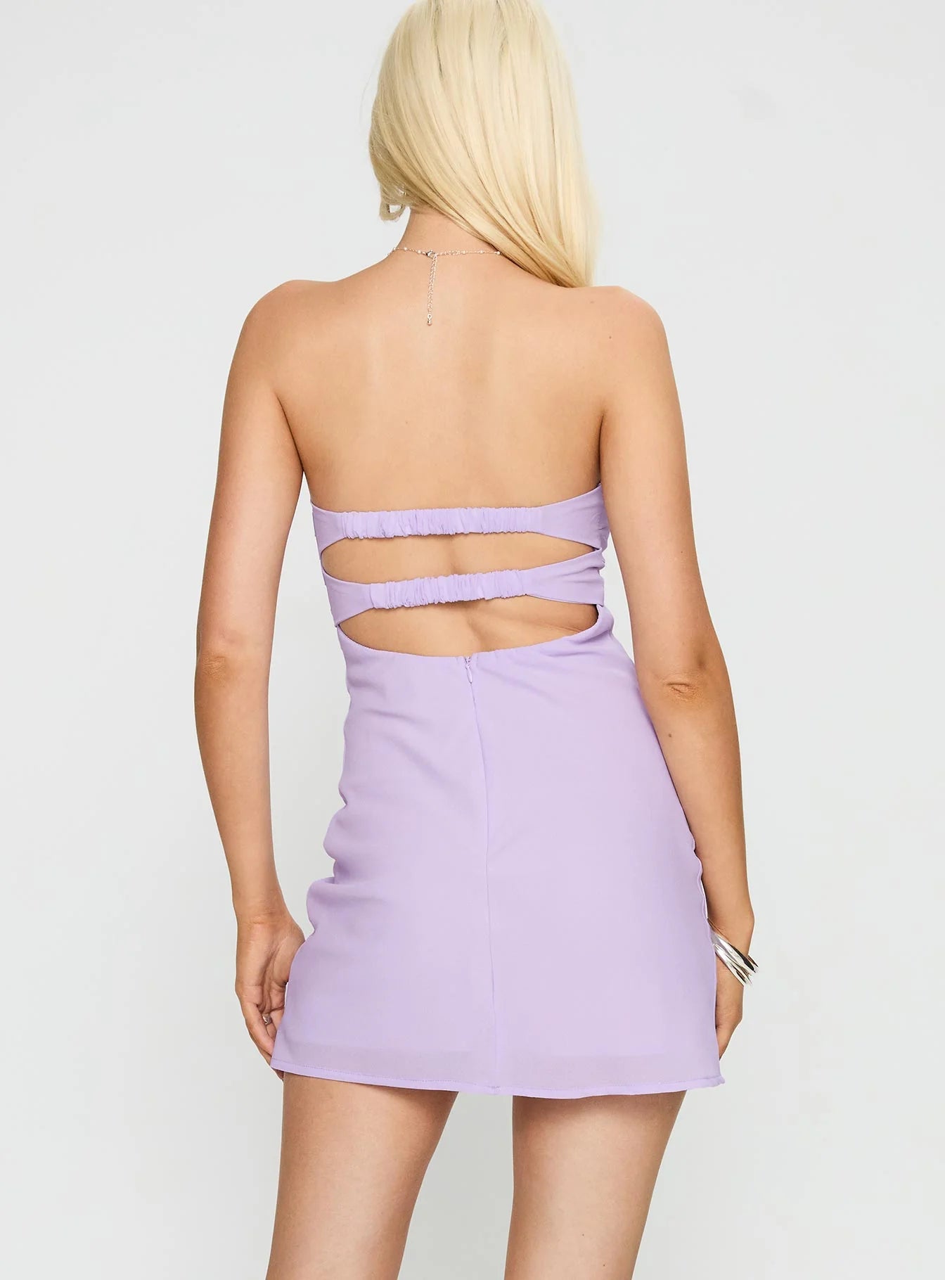 Back view of a lavender strapless mini dress showing the double cutout design and ruched straps.
