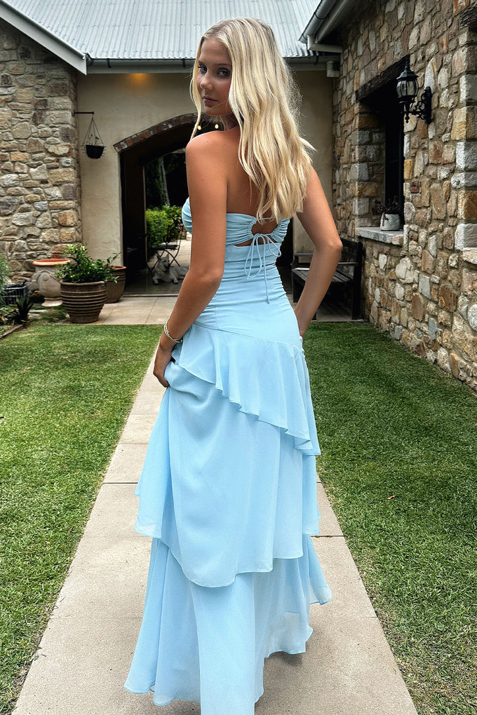 Full view of a woman wearing a sky blue strapless tiered ruffle maxi dress.
